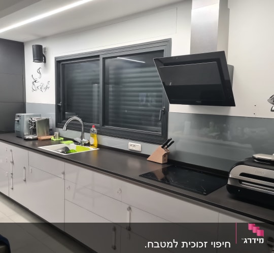זכוכית מגן על הקיר מעל השיש במטבח מודרני